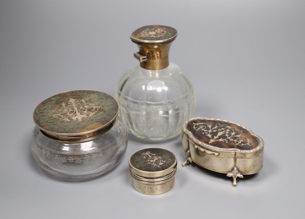 Three various tortoiseshell and silver pique-mounted glass toilet jars and a small silver circular box